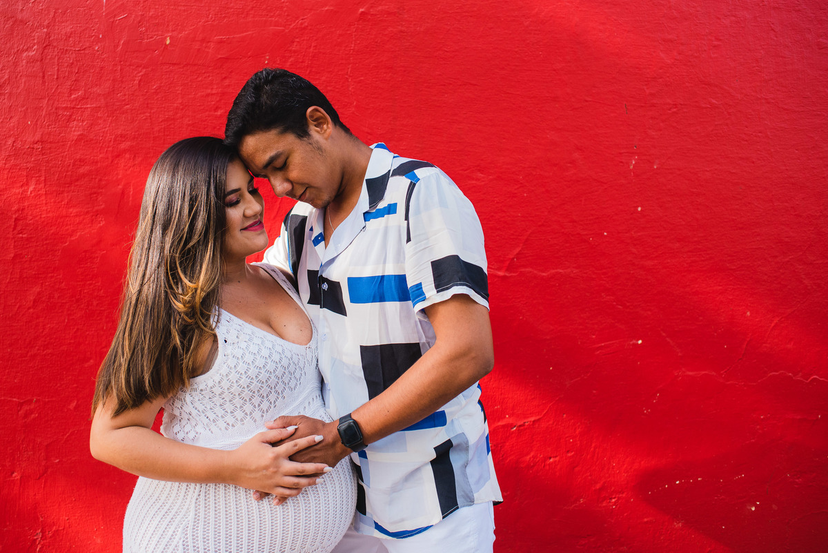 Foto de casal esperando seu primeiro filho, o pai coloca a mão na barriga da mamãe.