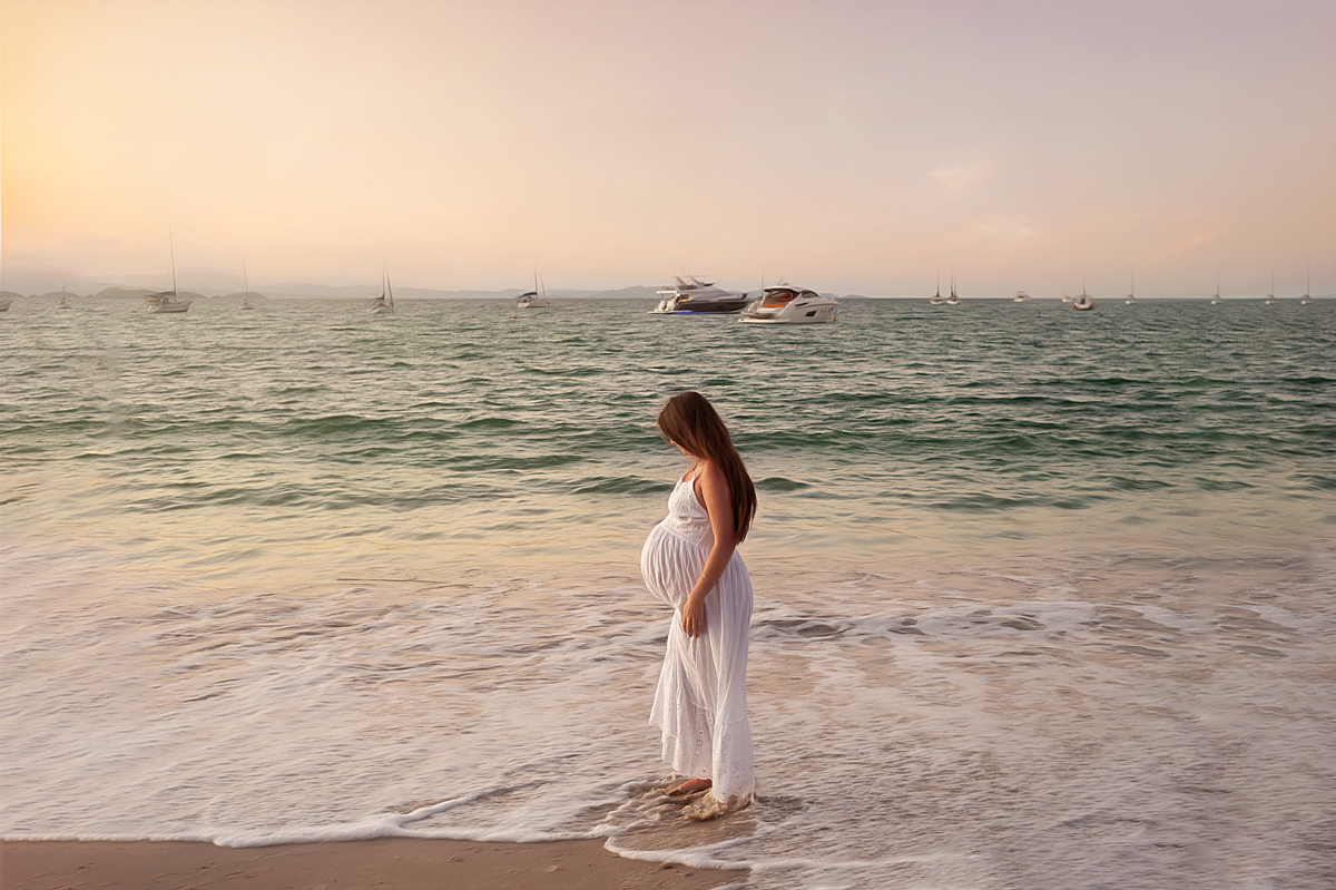 Grávida linda de vestido branco caminhando na praia