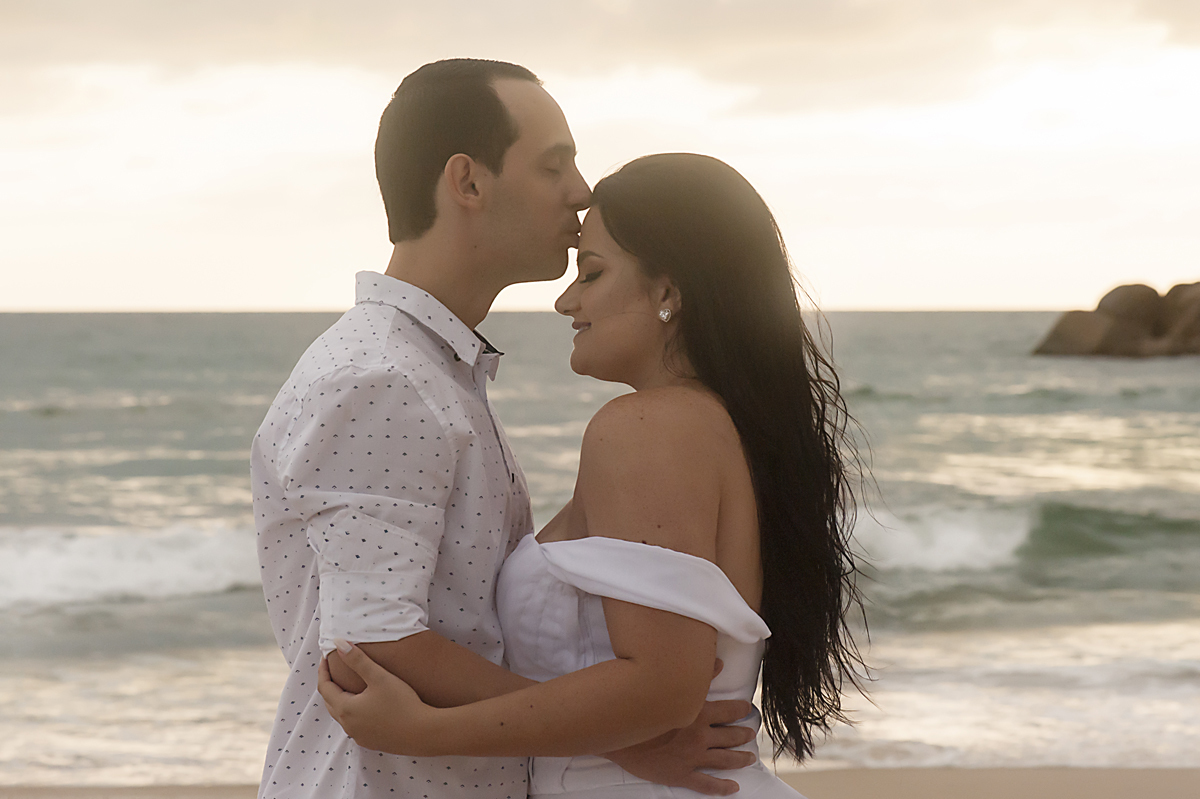 Noivo dá um beijo na testa da noiva na Praia Brava