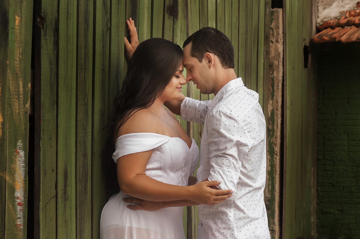 Casal pertinho encostado na casa de madeira verde