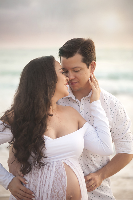 Casal bem pertinho se olhando e sorrindo ao nascer do sol na praia Brava