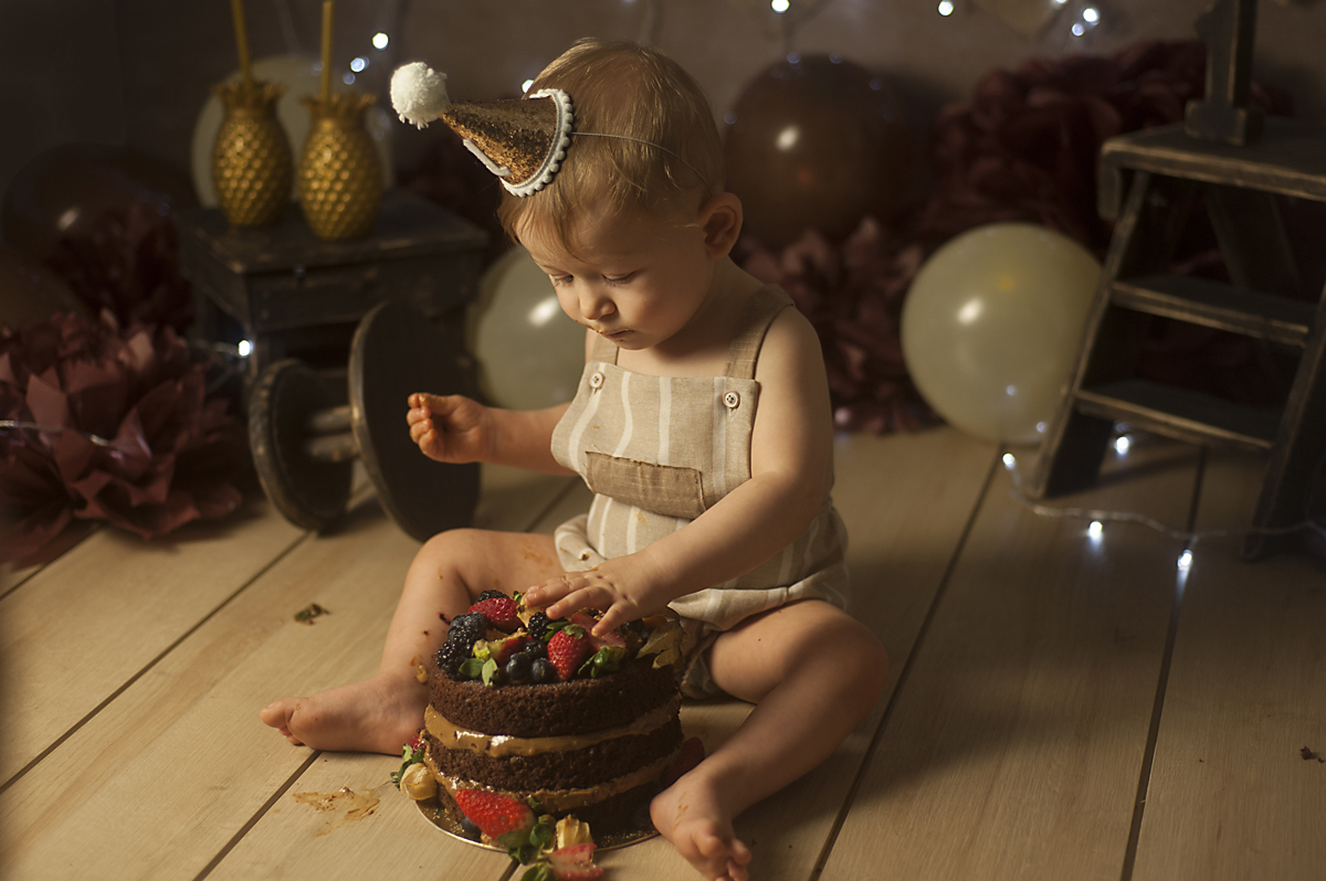Francisco usando roupa neutra coloca a mao no bolo naked cake de chocolate