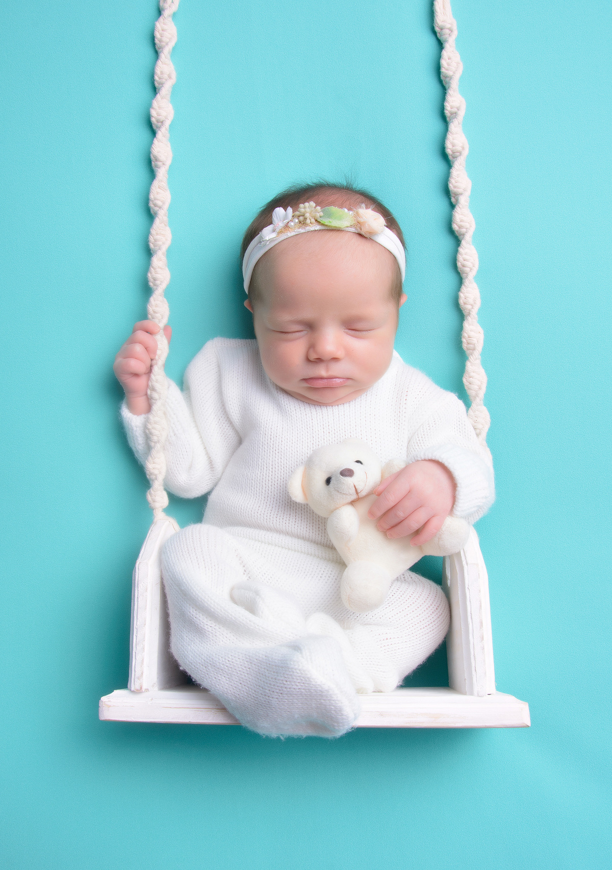 Sessão newborn de menina no balanço com urso