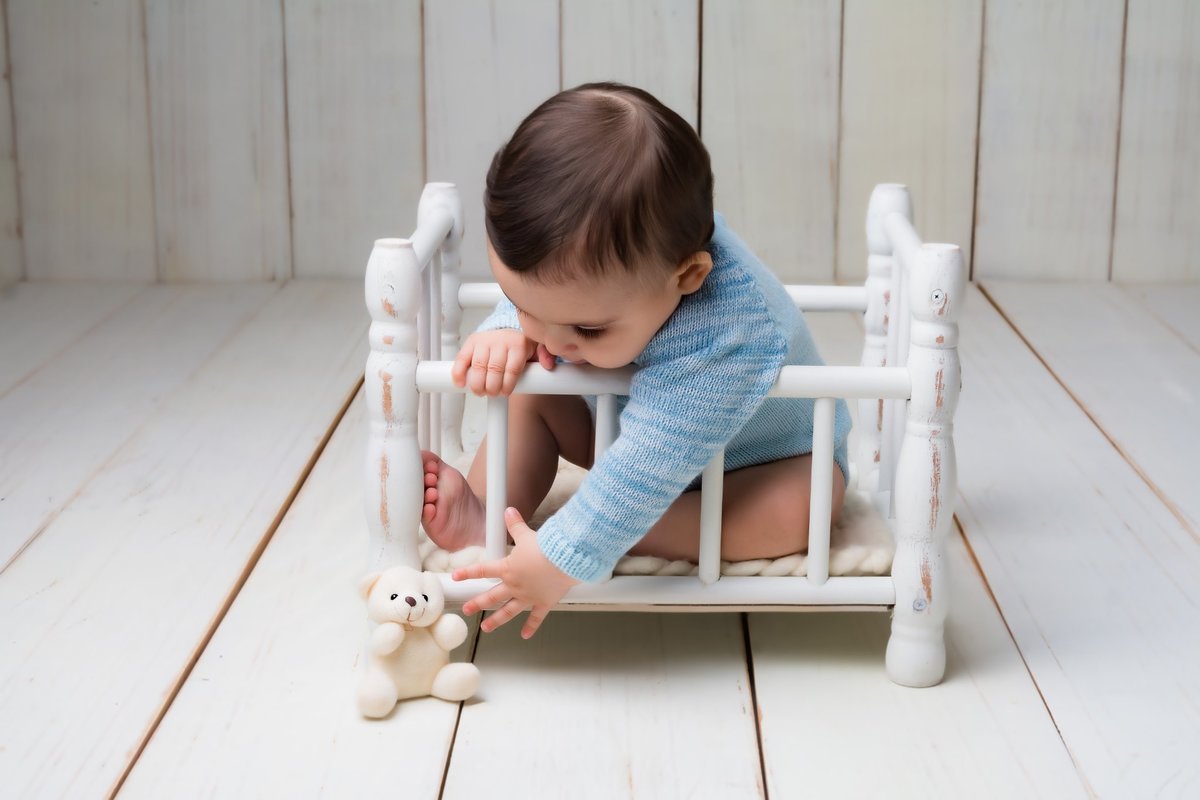 Bebê lindo quase pegando o ursinho no estúdio