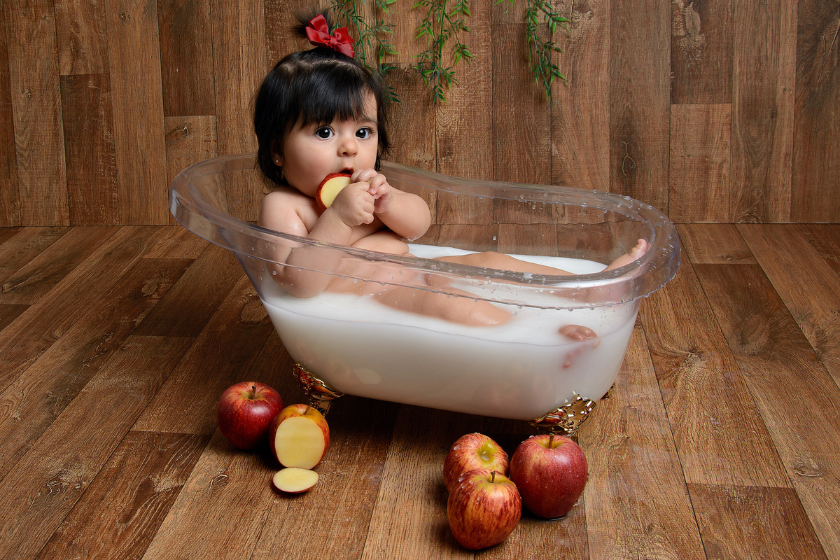 Nina deliciando da maçã no cenário do banho com a banheira 