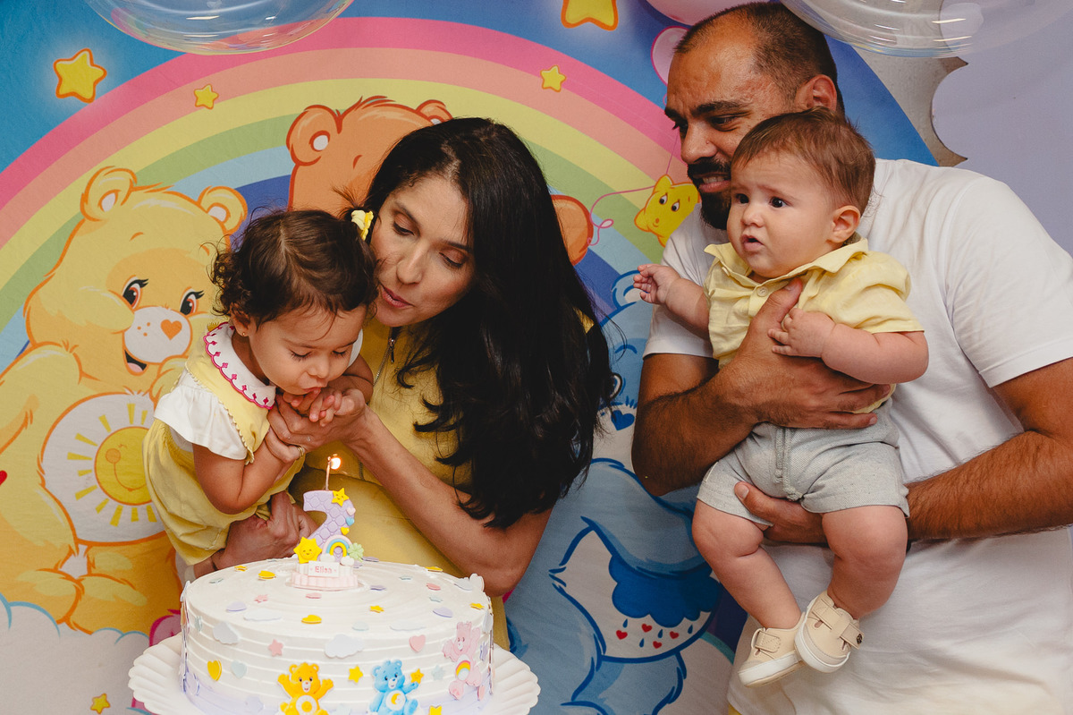 Família reunida enquanto aniversariante sopra a vela do bolo