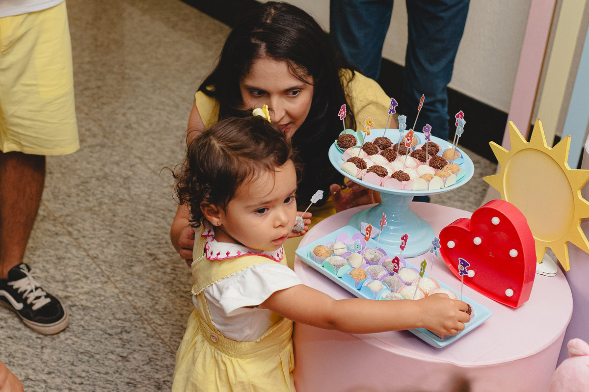 Menina pegando brigadeiro e mãe conversando com ela