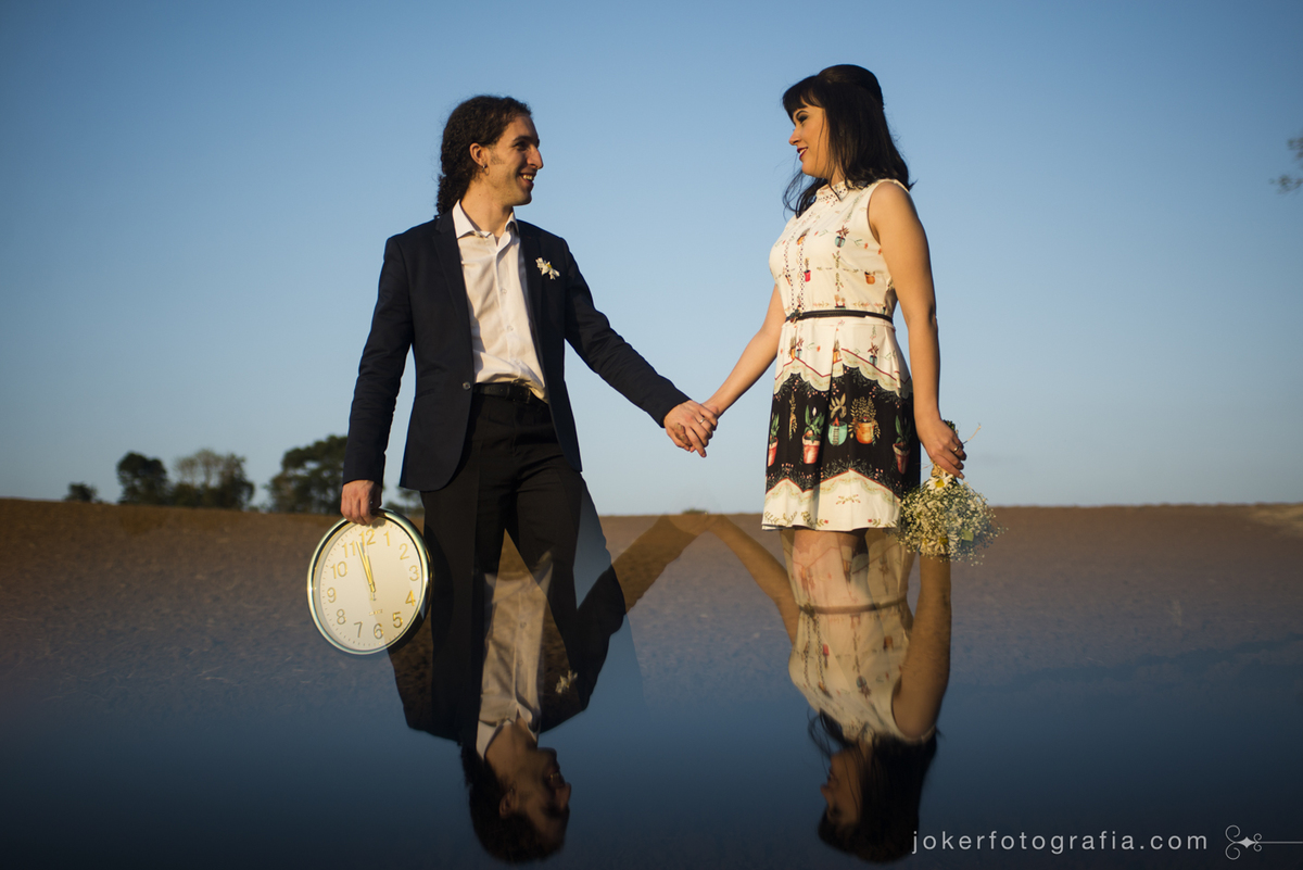 ensaio de casamento externo feito num campo com um relógio fica com visual surreal