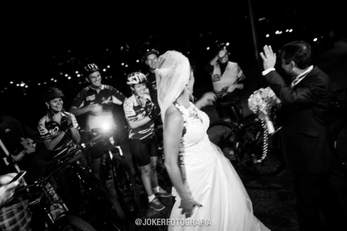 ciclistas passam em frente ao casal de noivos durante a festa de casamento