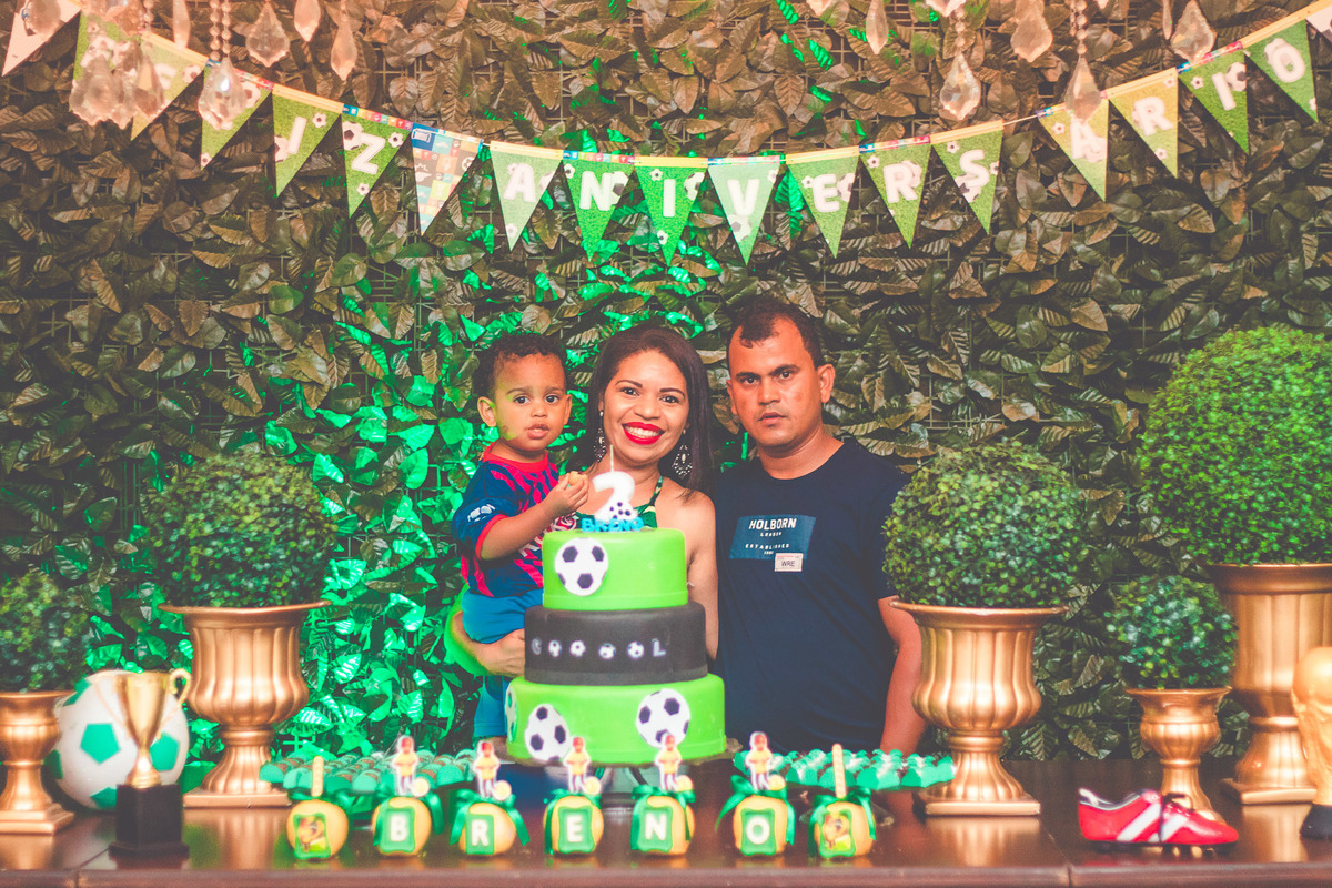criança e os pais em frente a bolo de aniversário comemorando 2 anos em festa infantil com tema de futebol