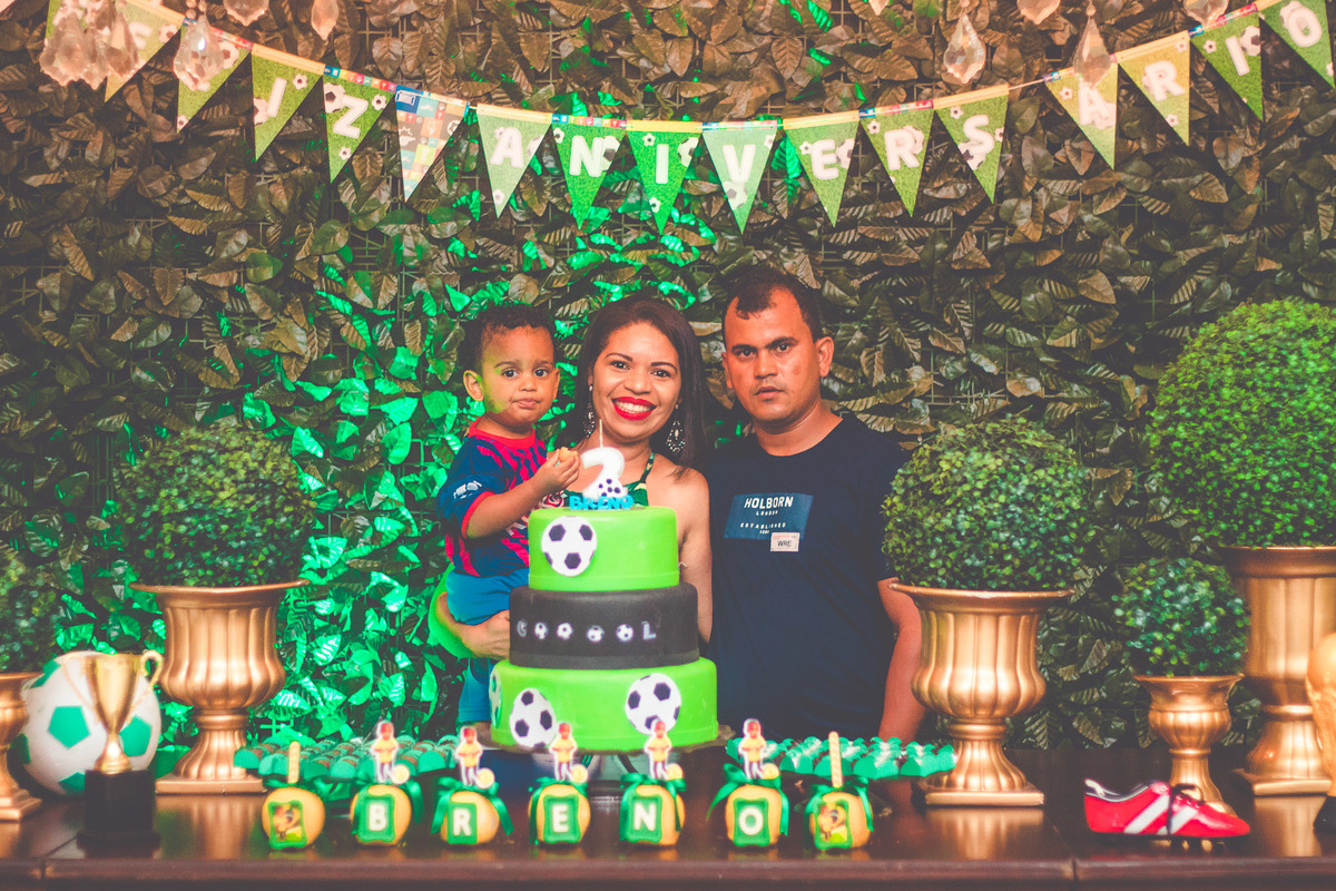criança e os pais em frente a bolo de aniversário comemorando 2 anos em festa infantil com tema de futebol