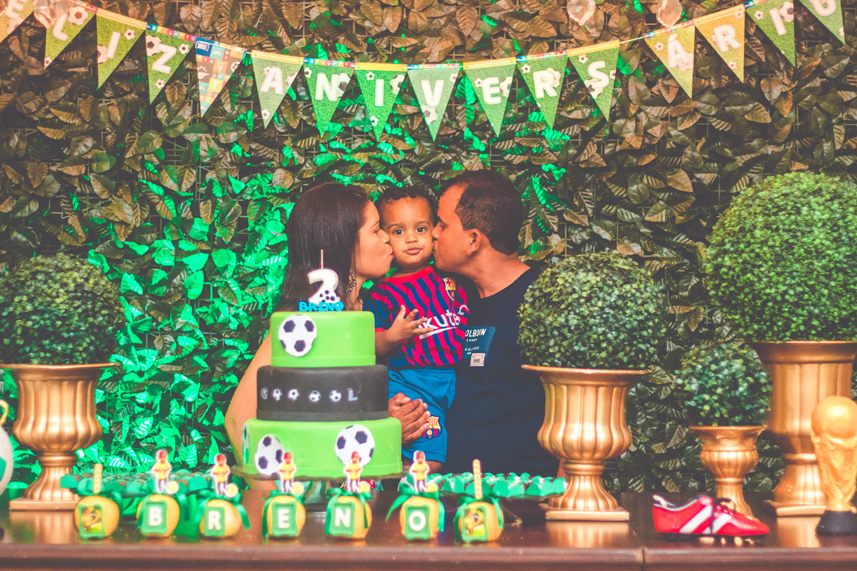 criança e os pais em frente a bolo de aniversário comemorando 2 anos em festa infantil com tema de futebol