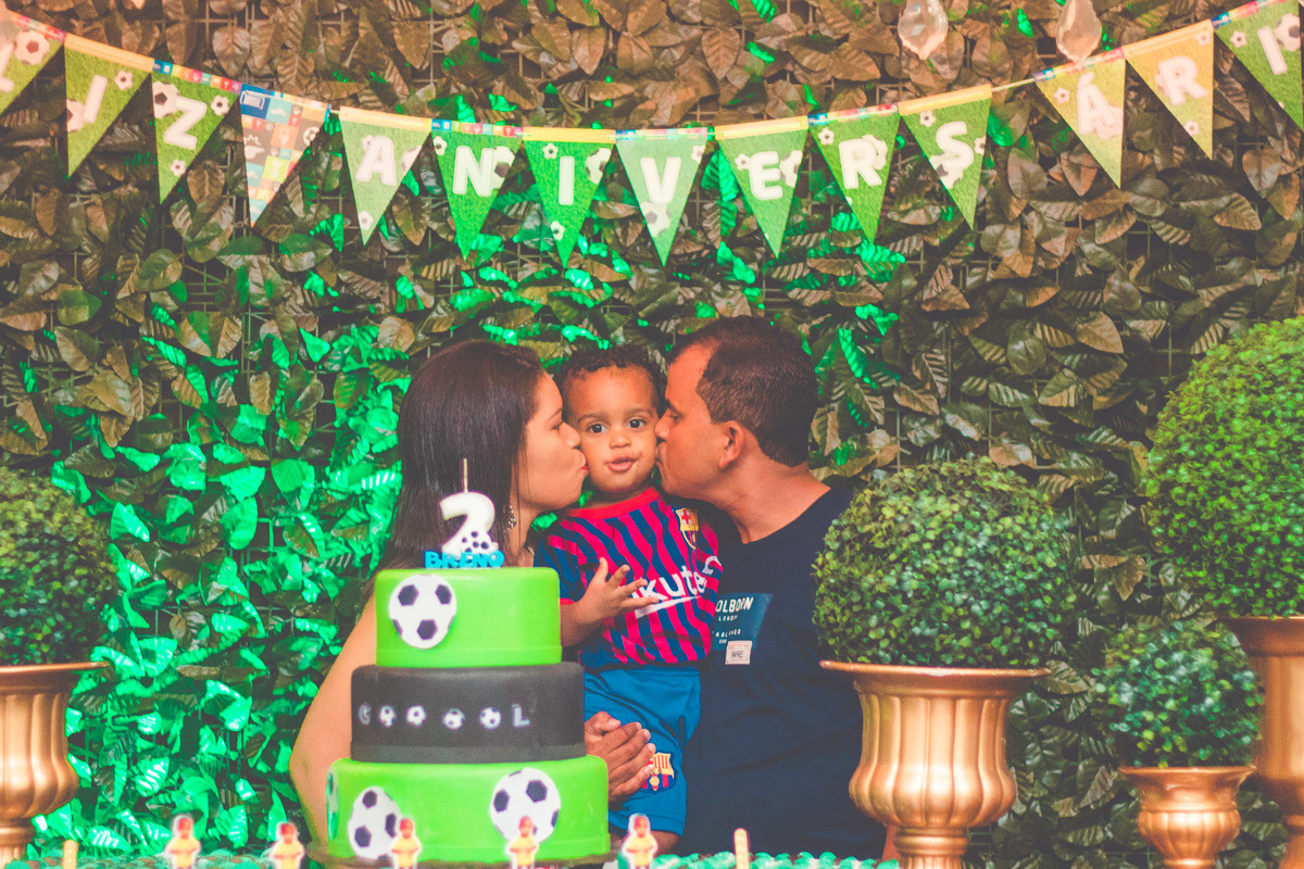 criança e os pais em frente a bolo de aniversário comemorando 2 anos em festa infantil com tema de futebol