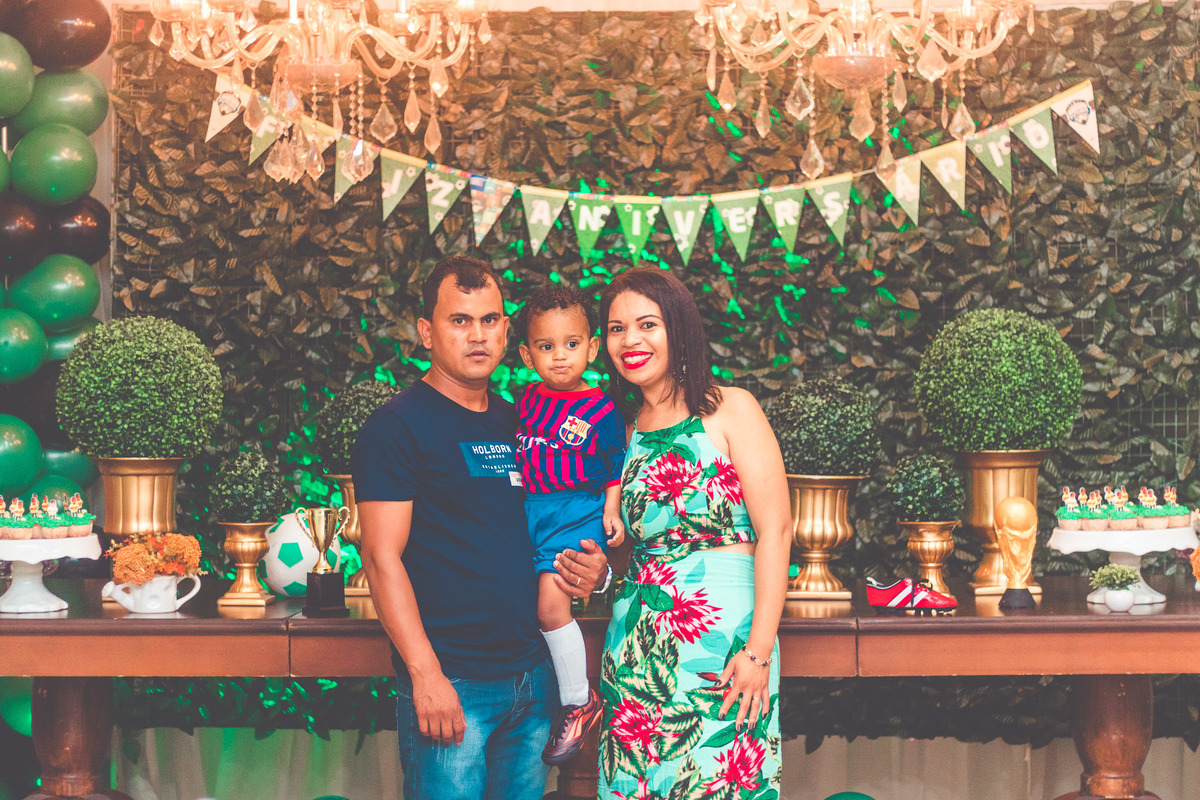 criança e os pais em frente a bolo de aniversário comemorando 2 anos em festa infantil com tema de futebol