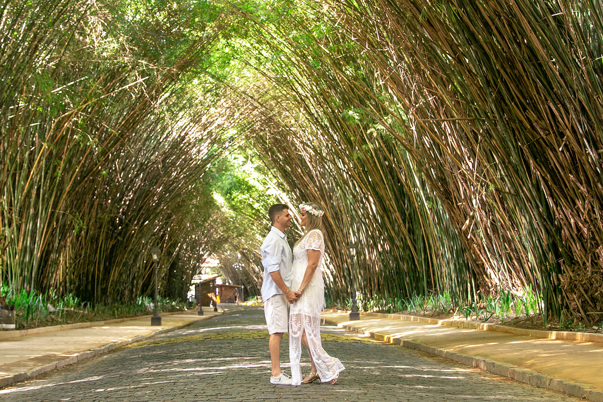 Casal apaixonado de mãos dadas  em uma estrada com bambus olhando um para o outro em ensaio pre wedding em Nova Friburgo no rio de janeiro 
