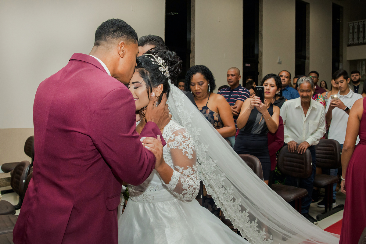 Noiva muito feliz sendo beijada pelo noivo durante cerimonia de casamento na igreja Metodista Central em Santo Antonio de Pádua no Rio de Janeiro.