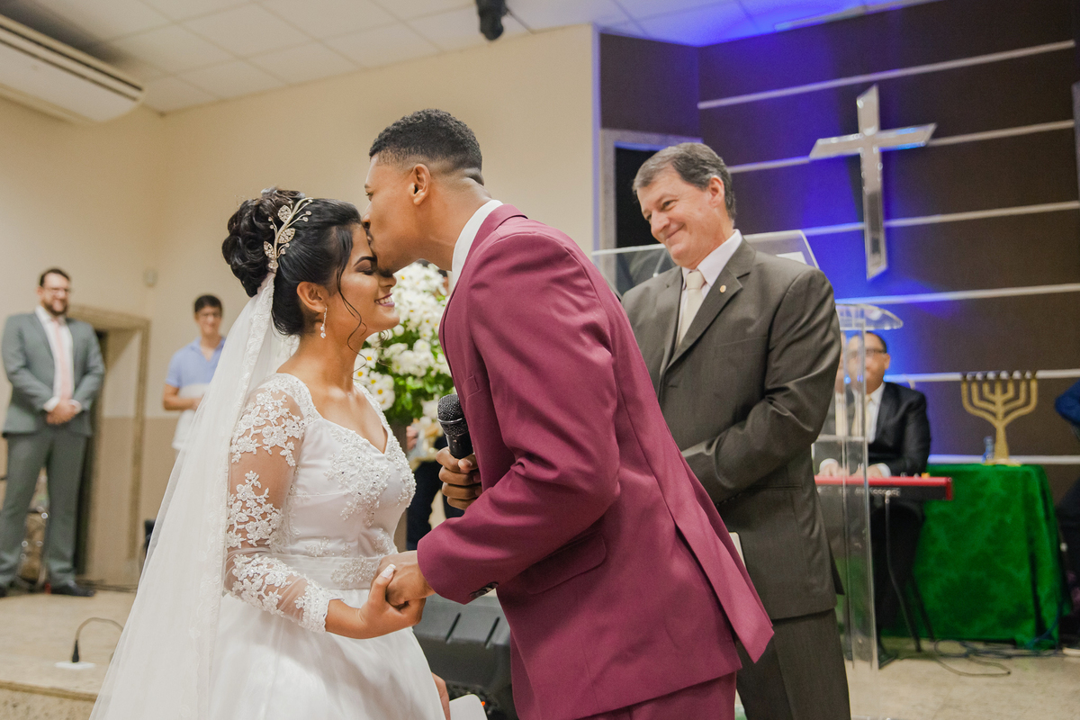 Noivo beijando a testa da noivo frente ao pastor em casamento na igreja Metodista Central em Santo Antonio de Pádua no Rio de Janeiro.