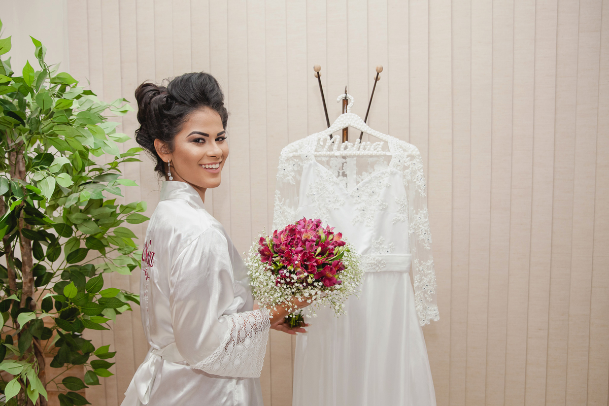 Noiva de roupão segurando seu buque no salão de beleza da Izalene momentos antos do grande sim em casamento em Santo Antonio de Pádua interior do Rio de Janeiro.