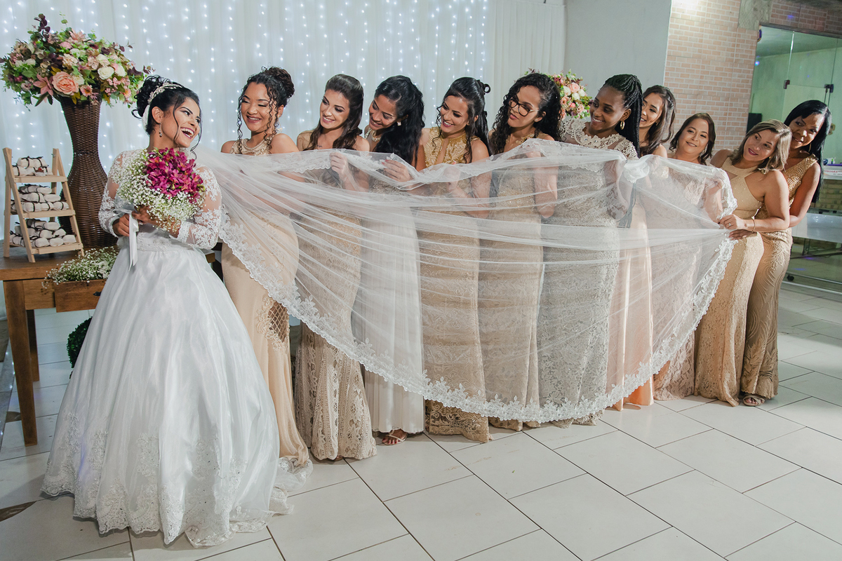 Madrinhas com vestido dourado segurando o véu da noiva durante a festa de casamento em Santo Antônio de Pádua no rio de Janeiro.