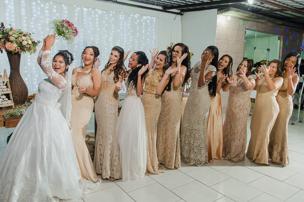 Noiva jogando seu buque para as madrinhas com vestido dourado  durante a festa de casamento em Santo Antônio de Pádua no rio de Janeiro.