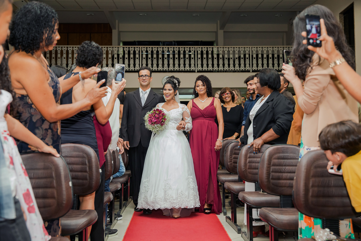 Noiva muito feliz entrando na igreja com seus pais em casamento na igreja Metodista Central em Santo Antonio de Pádua no Rio de Janeiro.