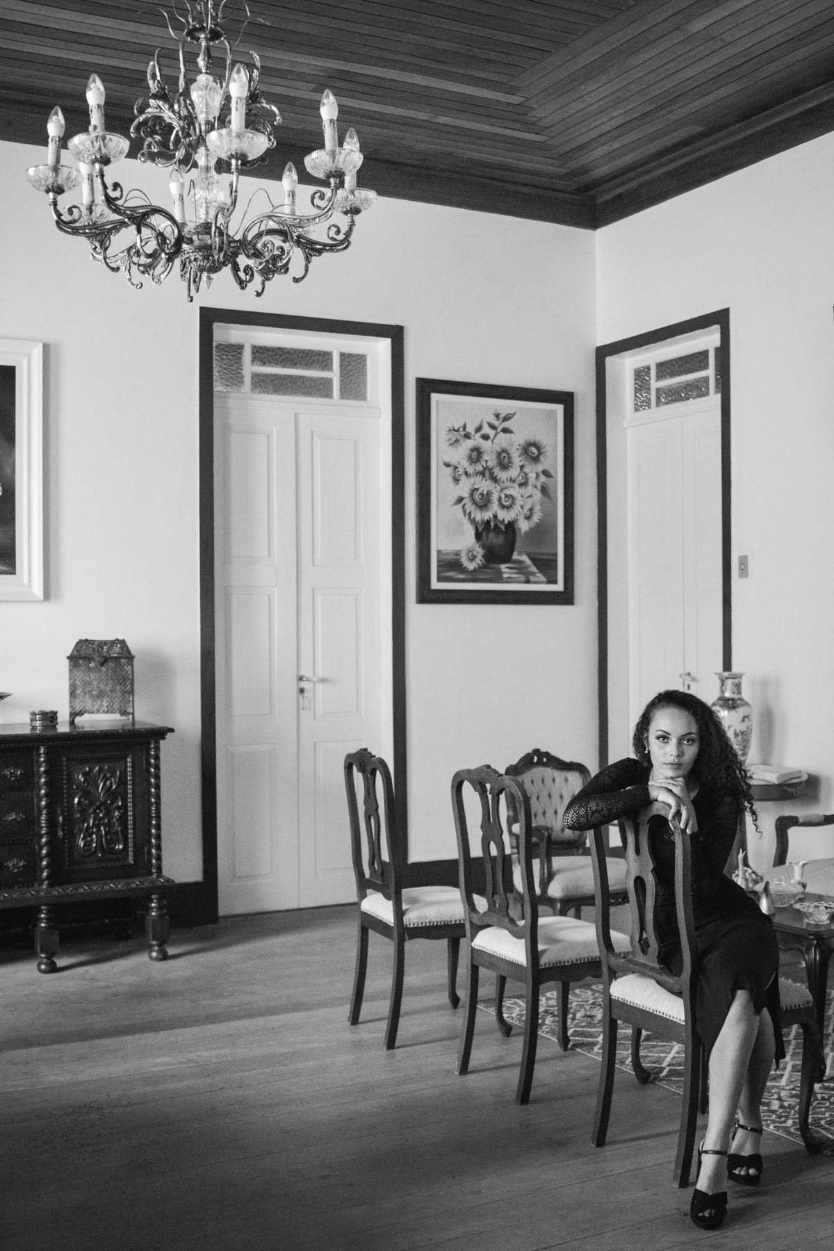 Foto em preto e branco de ensaio de 15 anos com debutante de cabelo cacheado com vestido preto em ensaio em Pádua RJ.