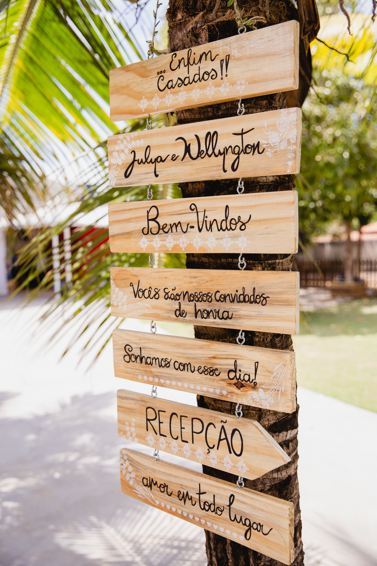 Plaquinha de madeira de seja bem vindo pendurada em coqueiro em casamento ao ar livre durantes a festa em Itaocara no Rio de Janeiro.