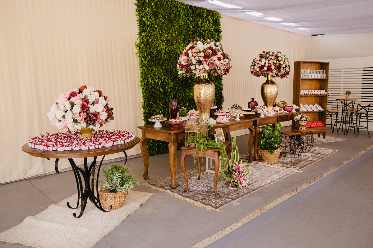 Mesa linda de casamento com flores naturais vermelhas bolo e doces durante festa ao ar livre em Itaocara no interior do Rio de Janeiro.