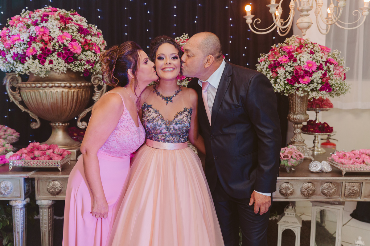 Aniversariante de 15 anos recebendo o carinho dos pais com beijo no rosto durante sua festa de 15 anos em Santo Antônio de Pádua no interior do Rio de Janeiro.