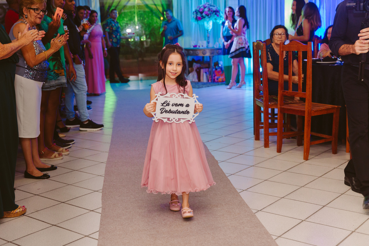 Dama de honra com plaquinha anunciando a entrada da aniversariante durante festa de 15 anos em Pádua no interior do Rio de Janeiro.