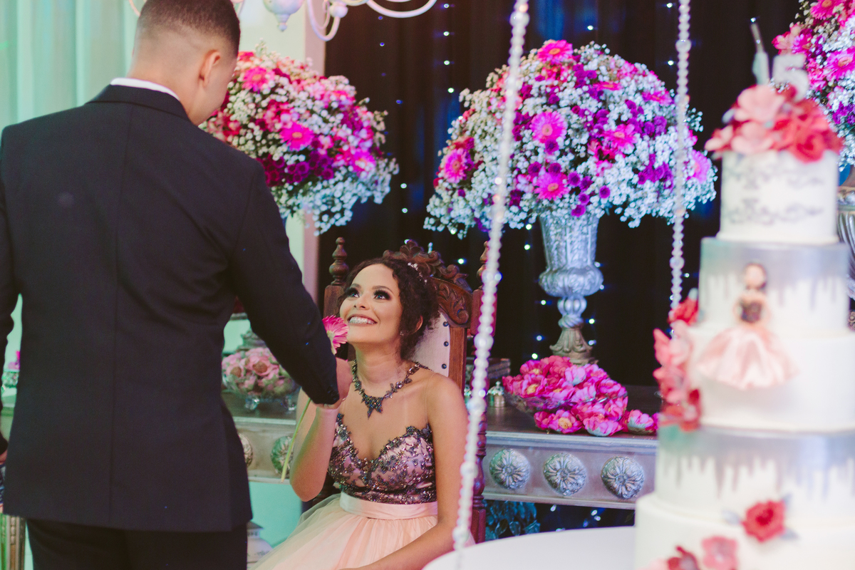Namorado de terno preto entregando uma flor para aniversariante de 15 anos durante festa de 15 anos em Santo Antônio de Pádua no Rio d Janeiro.