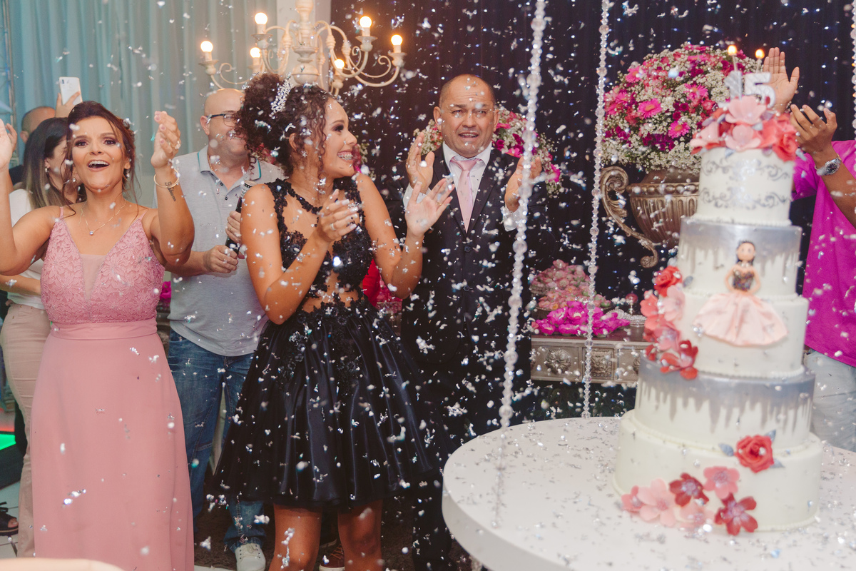 Hora dos parabéns em aniversário de anos com chuva de prata. Debutante com vestido preto curto durante festa de 15 anos em Santo Antônio de Pádua no interior do Rio de Janeiro.