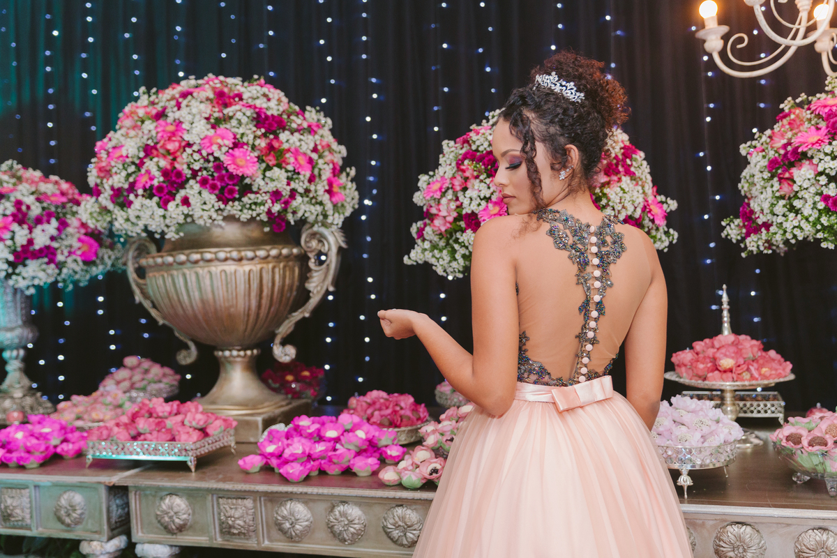 Aniversariante linda mostrando detalhes do seu vestido frente única com detalhe de laço nas costas. Durante festa de 15 anos em Santo Antônio de Pádua no Rio de Janeiro.