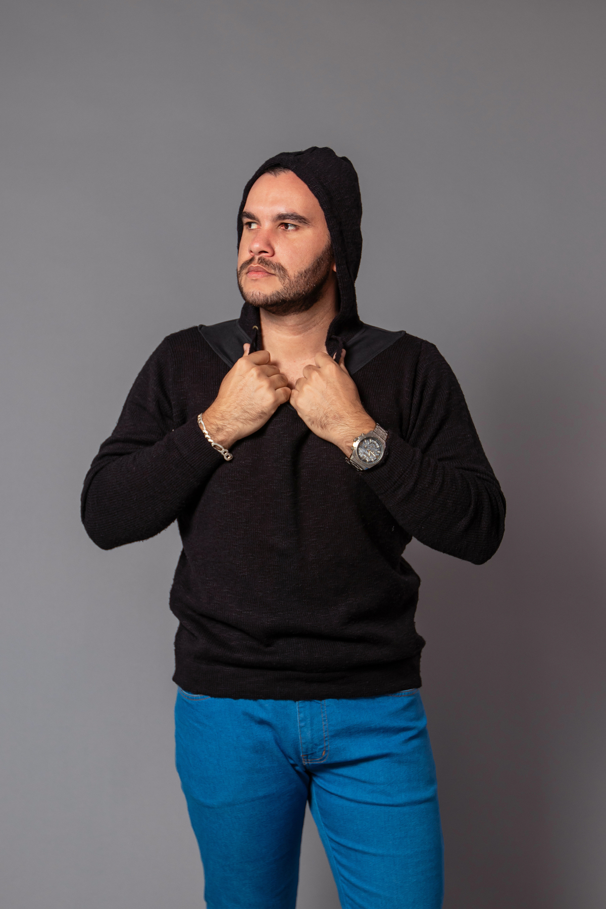João Vitor em seu seu ensaio masculino com calça jeans e camisa preta fazendo pose em studio fotográfico com fundo fotográfico na cor cinza em Santo Antônio de Pádua no Rio de Janeiro 