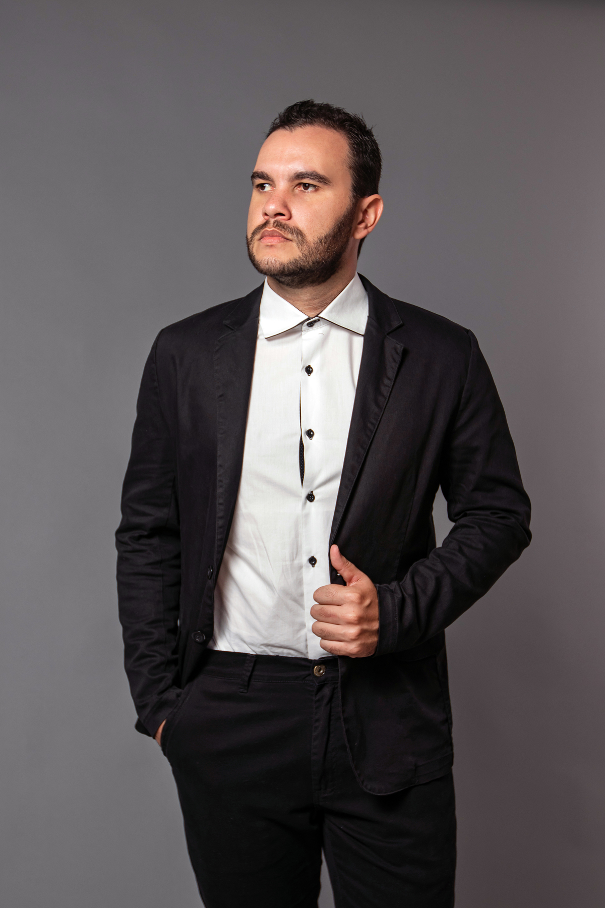 João Vitor em seu seu ensaio masculino em estúdio com terno  preto no fundo fotográfico cinza em Santo Antonio de Pádua no interior do RJ