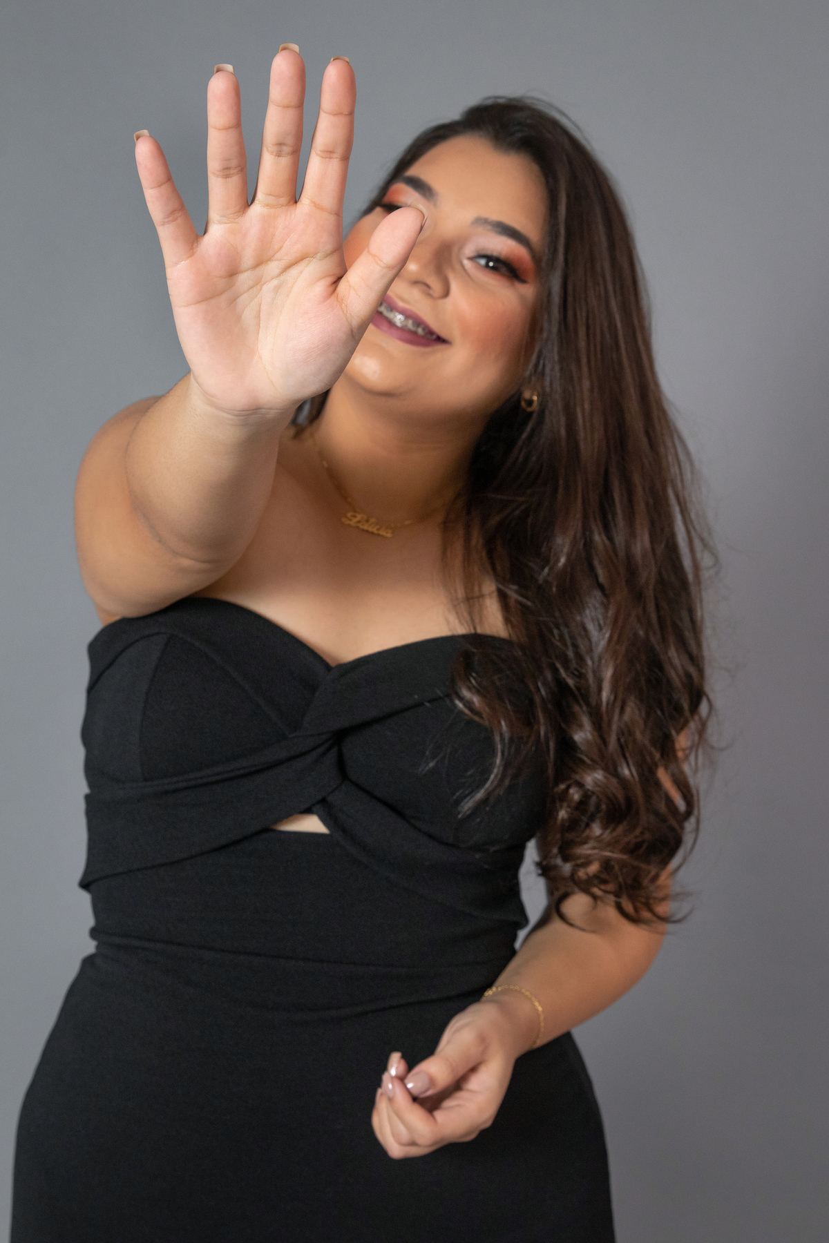 Ensaio feminino de 18 anos, com vestido preto, make perfeita em fundo cinza em estúdio em Santo Antônio de Pádua no Rio de Janeiro.