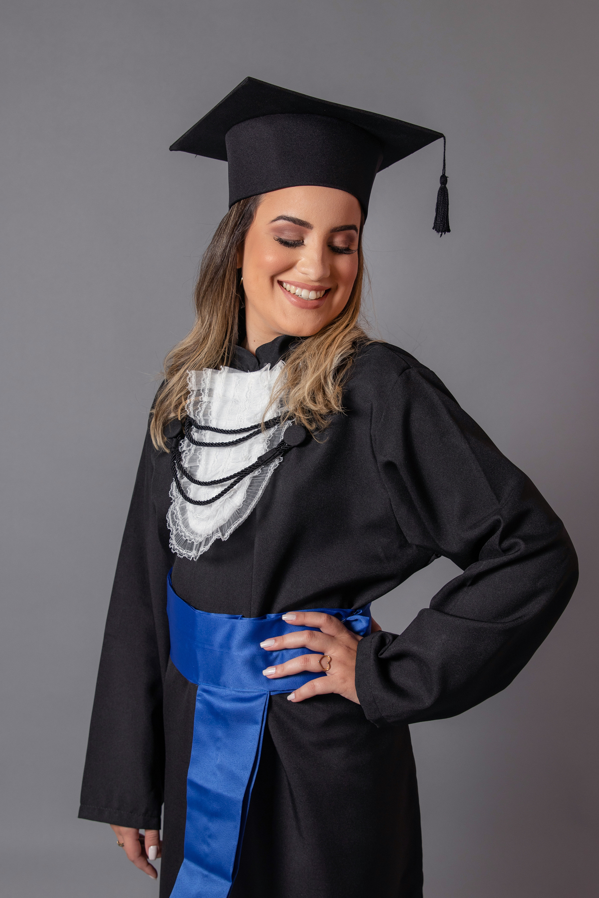 Formanda vestindo beca com faixa azul em seu ensaio de formanda em psicologia em estudio realizado em Santo Antônio de Pádua no RJ