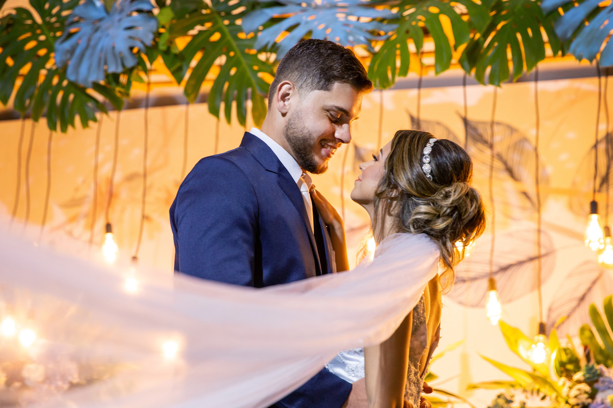 Vestido da noiva todo justo com um enorme véu e terno do noivo azul durante festa de casamento ao ar livre em Pádua interior do Rio de Janeiro.