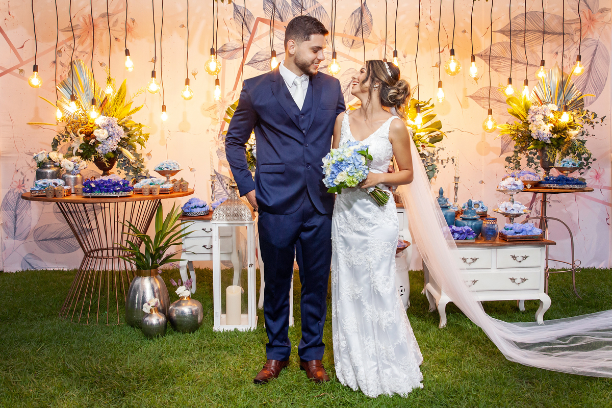 Vestido da noiva todo justo com um enorme véu e terno do noivo azul durante festa de casamento ao ar livre em Pádua interior do Rio de Janeiro.
