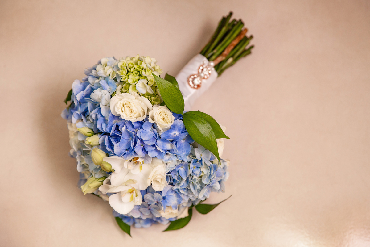 Fotos do buquet da noiva em orquidias brancas e hortênsias azuis durante em seu making of minutos antes do seu casamento no salão da Thais Dalet em Santo Antônio de Pádua - RJ.