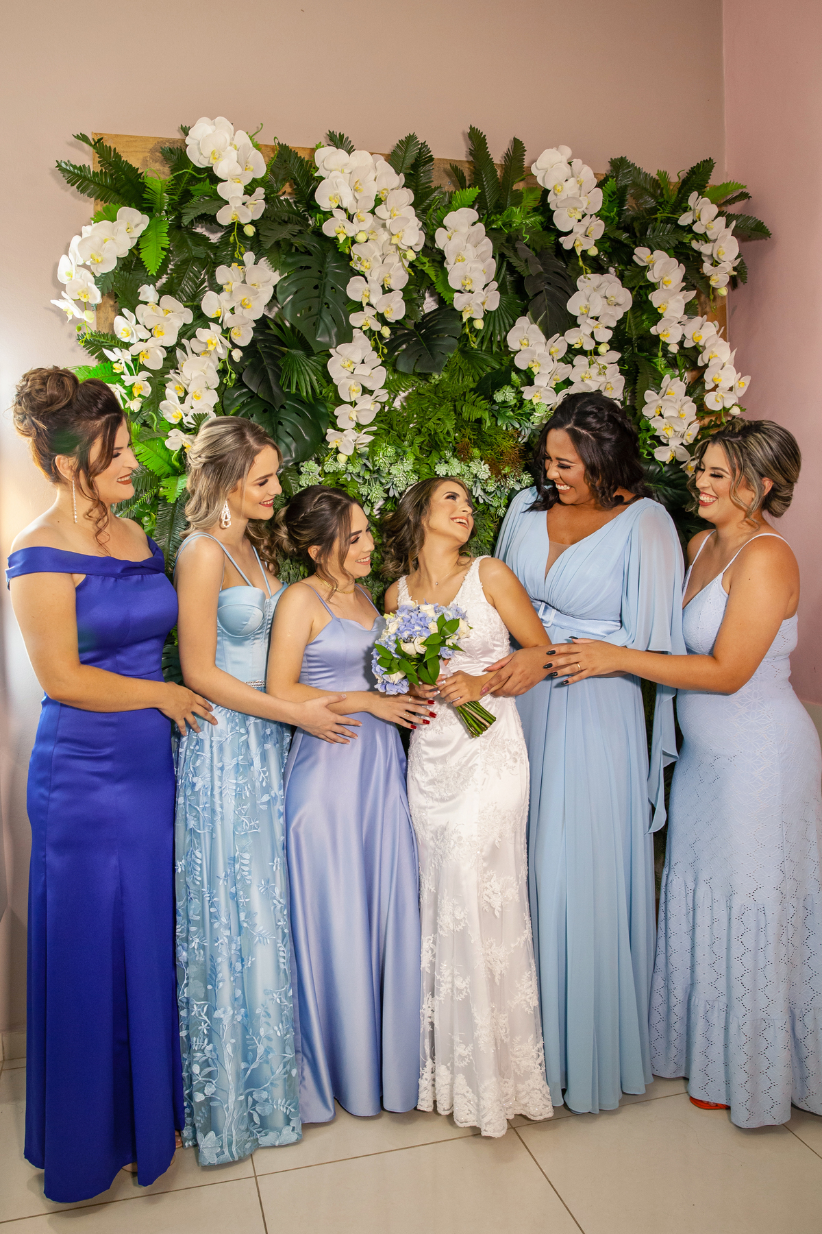 Madrinhas lindas com vestidos azuis ajudando a arrumar a noiva durante making off minutos antes do casamento no salão da Thais Dalet em Santo Antônio de Pádua - RJ.