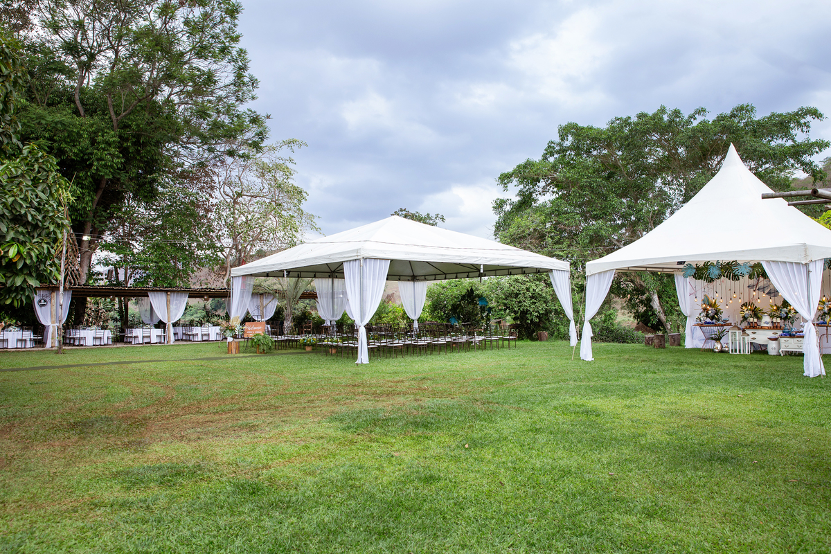 Fotos da decoração em um casamento lindo ao ar livre, decoração com muito verde e lâmpadas penduradas, noivo de terno azul em Santo Antônio de Pádua - Rj.