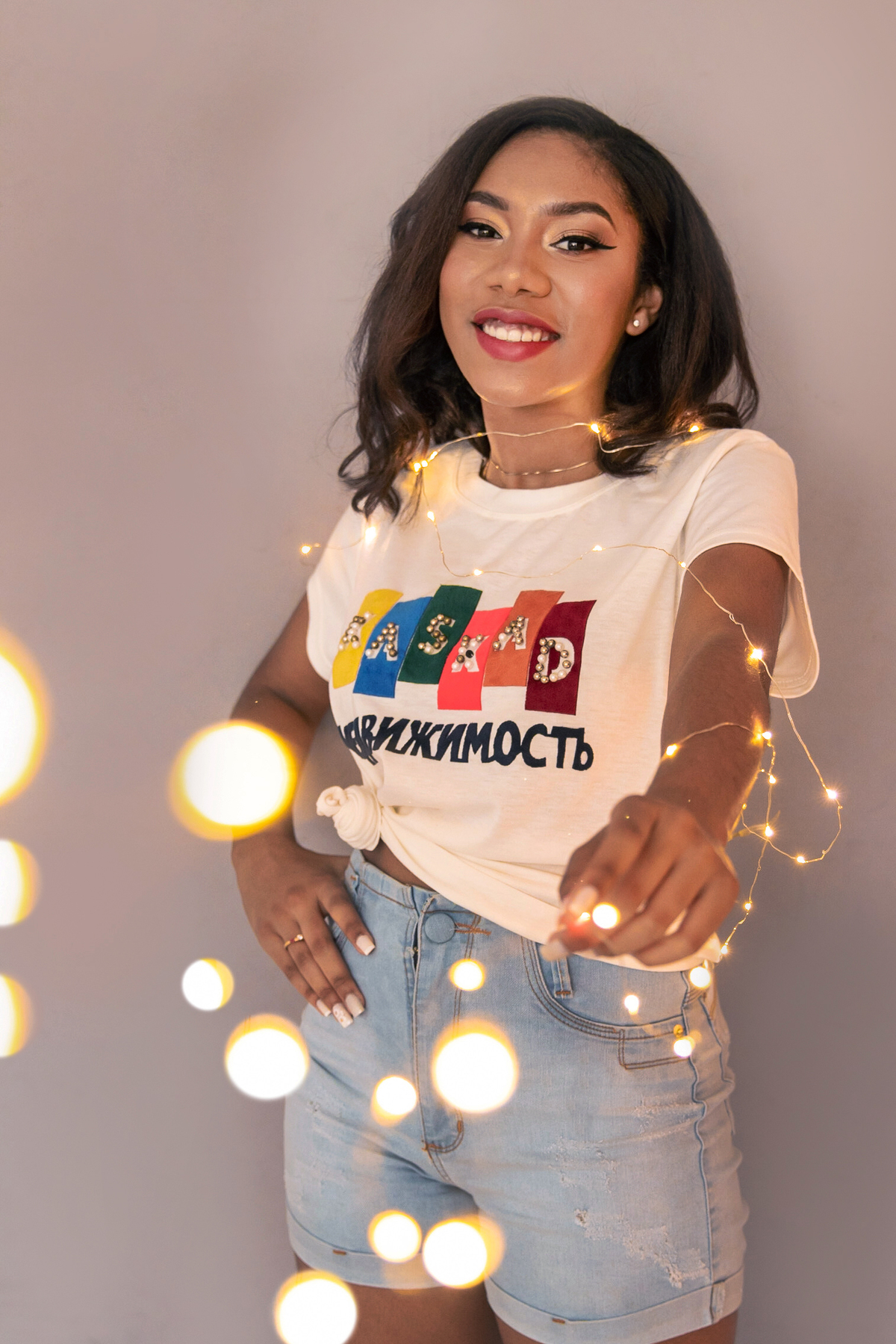 Ensaio 15 anos em estúdio, debutante short jeans e segurando fio de fada sorrindo para suas fotos de 15 anos em Santo Antônio de Pádua no interior do Rio de Janeiro.