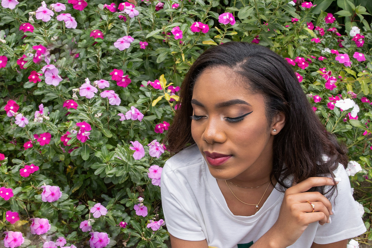 Ensaio 15 anos em estúdio, debutante short jeans no meio das flores coloridas sorrindo para suas fotos de 15 anos em Santo Antônio de Pádua no interior do Rio de Janeiro.