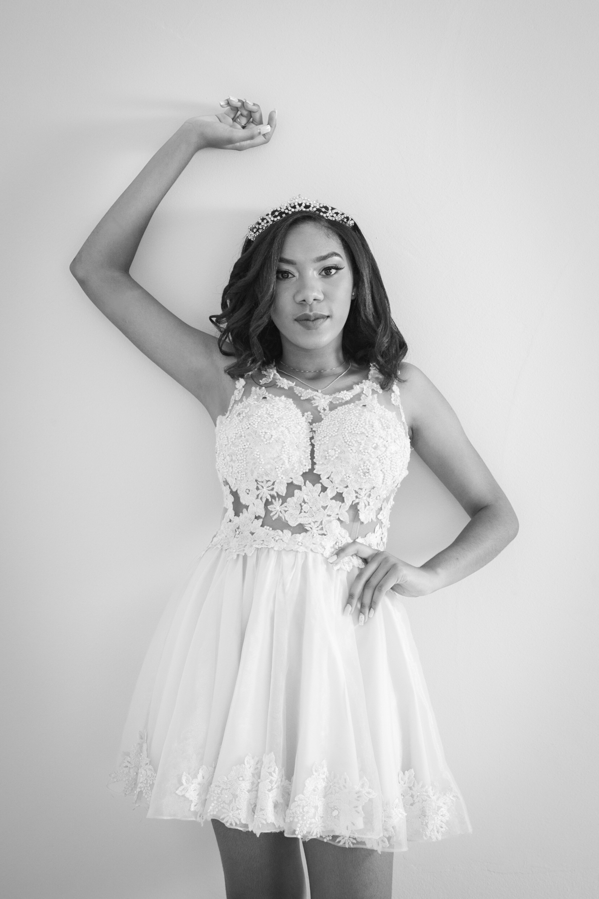 Debutante de 15 anos com vestido amarelo de renda fazendo seu ensaio em estúdio, encostada na parede e com a mão por cima da cabeça  em Santo Antônio de Pádua no interior do Rio de Janeiro. Foto preta e branca