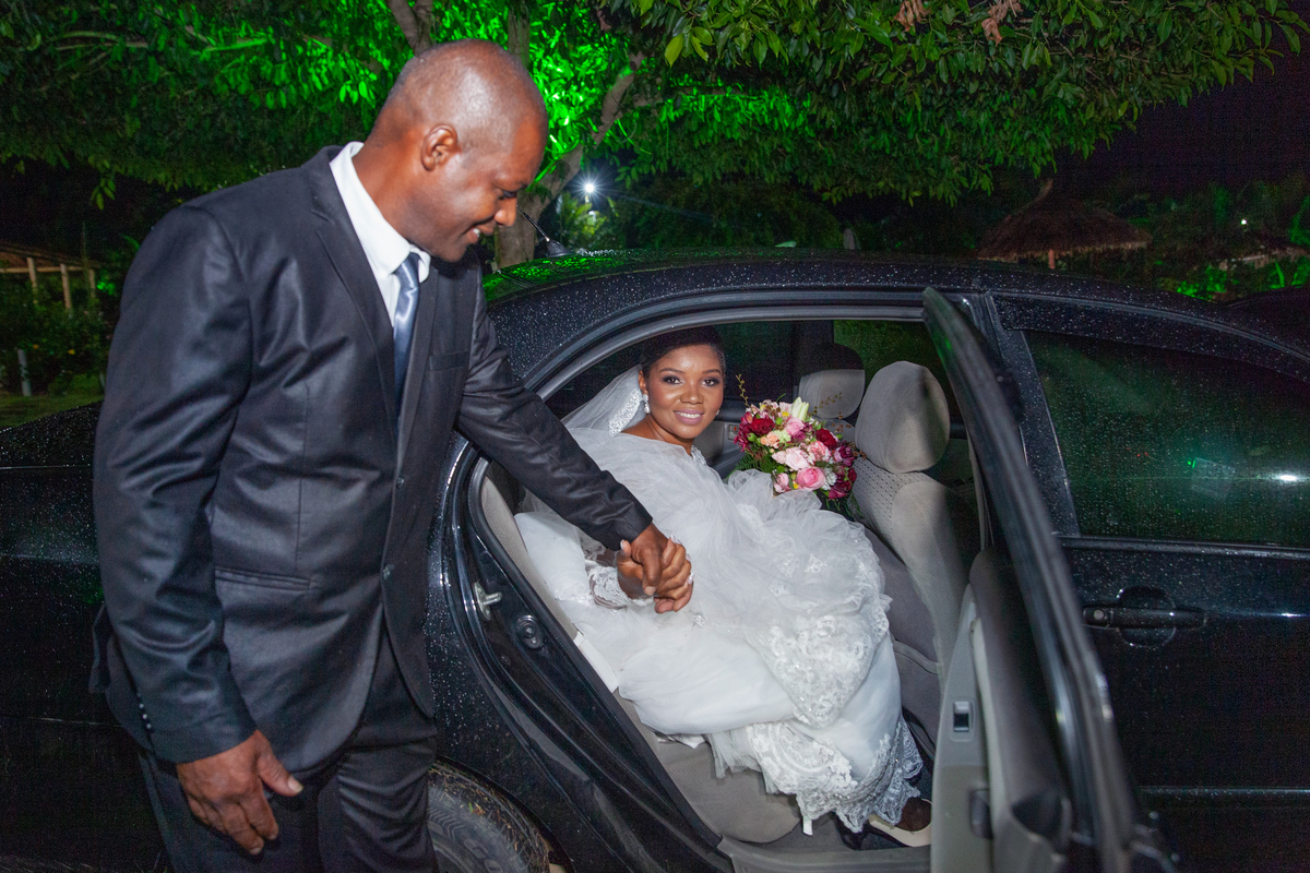 Noiva saindo do carro juntamente com seu pai para entrar na cerimonia do seu casamento durante a noite em um sitio em Cambuci no interior do Rio de Janeiro.