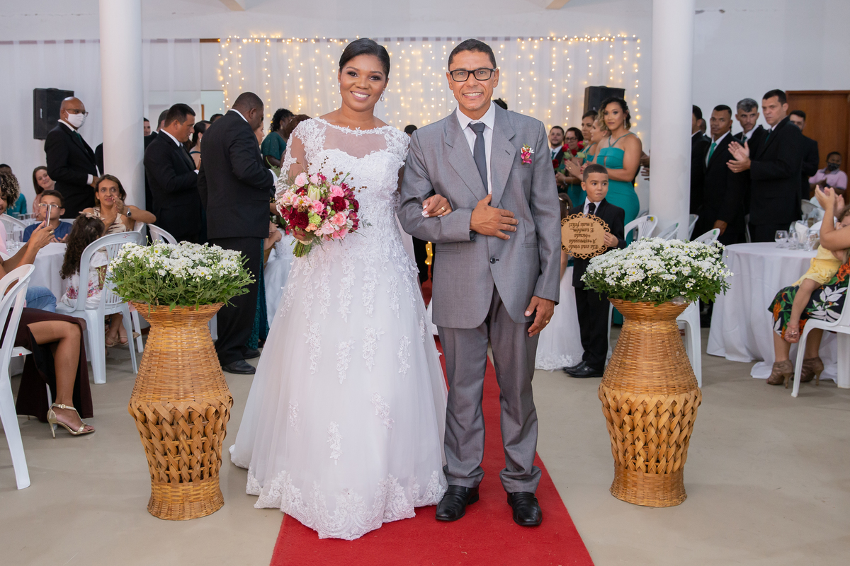 Noivos saindo da cerimônia de casamento sorrindo e felizes. Noiva com vestido de renda e véu lindo e noivo com terno cinza. casamento durante a noite em um sitio em Cambuci no interior do Rio de Janeiro.