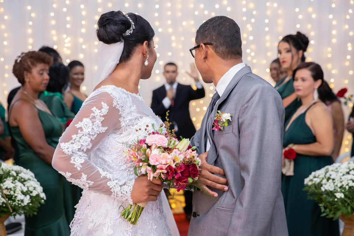 Noivos saindo da cerimônia de casamento sorrindo e felizes. Noiva com vestido de renda e véu lindo e noivo com terno cinza. casamento durante a noite em um sitio em Cambuci no interior do Rio de Janeiro.