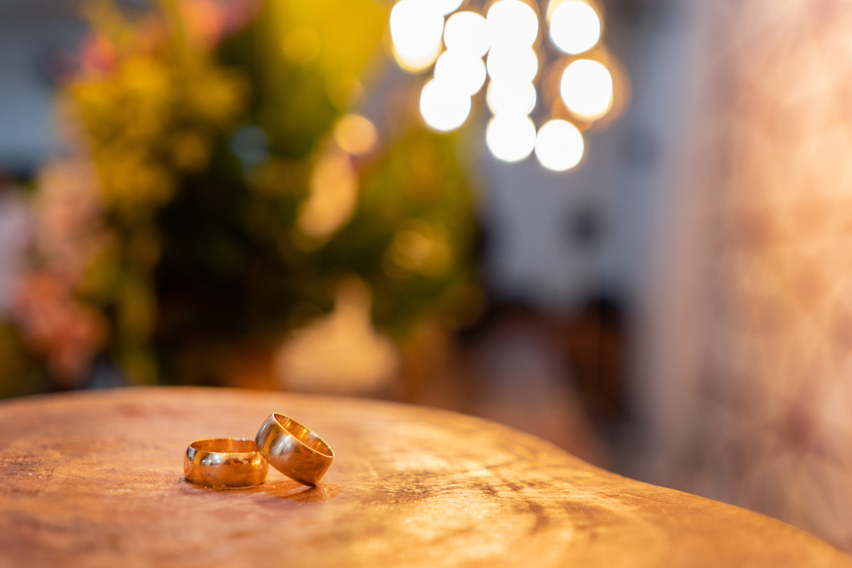 Foto das alianças em casamento durante a noite em Cambuci, pegando detalhes da decoração da festa no interior do Rio de Janeiro.