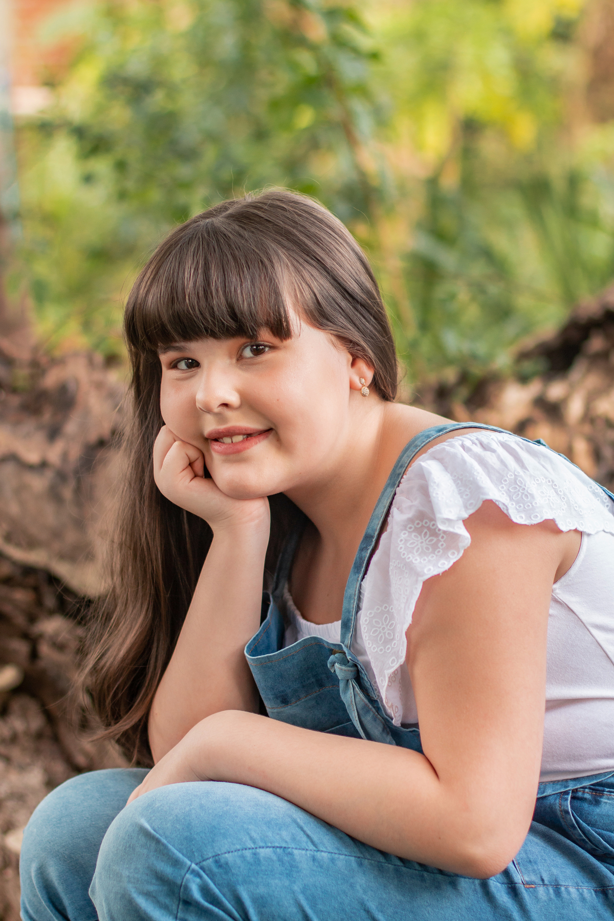 Ensaio de fotos ao ar livre com muito verde, menina com macacão jeans linda, toda feliz comemorando seu aniversário de 10 anos com óculos decoração estúdio em Santo Antônio de Pádua no Rio de Janeiro.